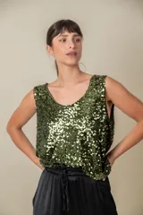 Blusa sin mangas confeccionada en tela cubierta de lentejuelas doradas y plateadas, con escote redondo y corte holgado.