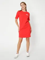 Vestido rojo de algodón con cuello redondo y mangas cortas. Presenta un logo de Tommy Hilfiger bordado en blanco en el pecho y la bandera de la marca bordada en la manga.