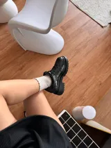 Zapato mocasín negro de cuero charol con diseño tipo reptil, cordones y suela track.