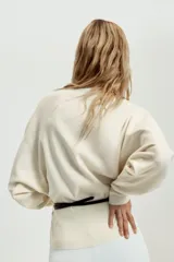 Jersey de punto negro con cuello barco y mangas largas amplias. Presenta un diseño ajustado en la cintura con un cinturón fino integrado que incluye una hebilla metálica dorada.
