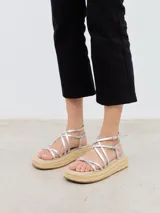 Sandalia plateada con plataforma de esparto, tiras finas con hebilla y cierre al tobillo.