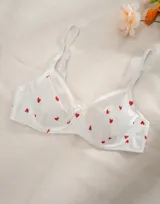 Soutien blanco con estampado de corazones rojos, con breteles finos regulables y moño decorativo en el centro.