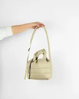 Bolso pequeño color beige, acolchado, con doble asa corta y correa larga ajustable.