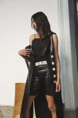 Bermuda de cuero color marrón oscuro con efecto desgastado, tiro medio, cierre frontal con botón y bolsillos.