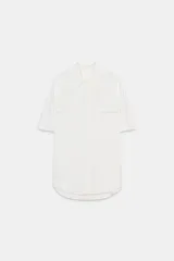 Camisa de cuello solapa y manga corta, confeccionada en tejido satinado. Presenta falsos bolsillos con solapa en el delantero, bajo asimétrico y cierre frontal con botones.