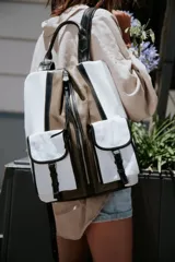 Mochila de cuero color marrón y blanco con cierre de cremallera y dos bolsillos frontales con cierre de hebilla.