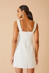 Vestido corto blanco de tejido texturizado, con breteles anchos y escote cuadrado.