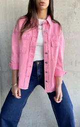 Sobrecamisa rosa de denim con terminaciones desflecadas, cuello camisero, cierre frontal con botones metálicos, dos bolsillos de parche en el pecho y mangas largas con puños abotonados.