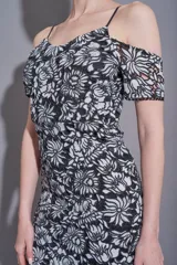 Vestido corto negro con estampado floral blanco, mangas cortas con hombros descubiertos y breteles finos.