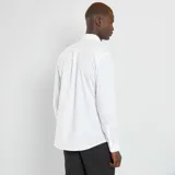 Camisa blanca de corte recto, con cuello clásico y mangas largas.