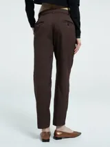 Pantalón sastrero de corte recto, color marrón, con cierre frontal, botón oculto, pasacintos y bolsillos laterales.