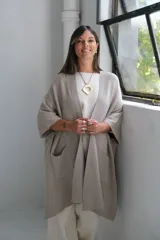 Poncho abierto de tejido de punto en color visón, con diseño holgado, mangas cortas y bolsillos frontales aplicados.