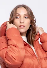 Campera puffer de nylon color negro con capucha, cierre frontal y bolsillos laterales. Presenta un bolsillo adicional con solapa en la manga izquierda y puños elásticos.