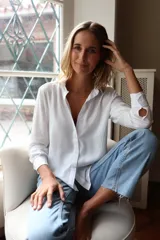 Camisa de fibrana blanca con cuello clásico, cierre frontal de botones y mangas largas con puños abotonados. Presenta un diseño minimalista y versátil.