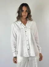 Camisa blanca de manga larga con cuello en V y volados desflecados a lo largo de la botonadura frontal.