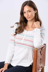 Remera t-shirt de algodón con rayas horizontales en tonos pastel (rosado, azul, beige y verde) sobre fondo blanco. Tiene cuello redondo con botones frontales y aberturas laterales.