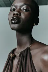Body entallado de poliamida color marrón, con escote profundo y cuello metálico tipo choker integrado. Presenta un diseño sin mangas con frunces en el busto.
