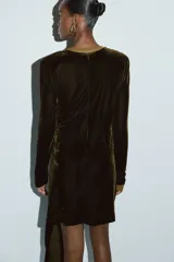 Vestido mini de velour con escote redondo y mangas largas con hombreras. Presenta un diseño ajustado con detalle de drapeado, nudo lateral y una tira larga que cae sobre la falda. Incluye cierre oculto en la espalda.