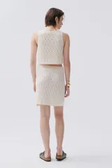 Falda corta de tejido calado color crudo con cintura elastizada y cordones laterales.