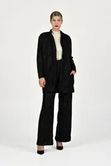 Conjunto de dos piezas en color negro con sutiles destellos brillantes. El saco es de corte recto, tipo cárdigan, con solapas y bolsillos frontales. El pantalón es de corte amplio y tiro alto.