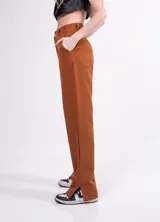 Pantalón sastrero de tiro alto color marrón, con pinzas delanteras, bolsillos laterales y traseros, y tajito lateral. Corte palazzo.