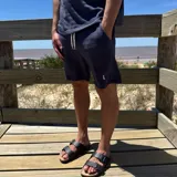 Short azul marino de tejido rústico con cordón ajustable en la cintura y logo bordado en blanco.