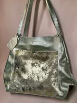 Bolso tipo tote Chabas confeccionado en cuero genuino color plateado, con un bolsillo frontal texturizado en tonos metalizados y doble asa superior para el hombro.