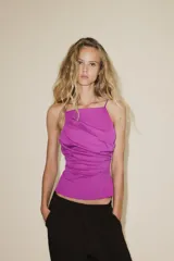 Top color fucsia de escote recto y tirantes finos, con detalle de pliegues y espalda descubierta. Cierre con lazadas en la espalda.