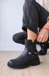 Bota corta negra de cuero, con caña media, hebilla lateral y suela track.