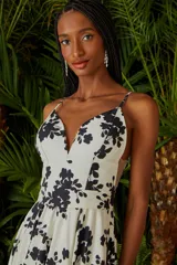 Vestido largo de fiesta color blanco con estampado de flores negras, escote en V y breteles finos.