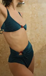 Top de bikini color bordó con textura acanalada, breteles anchos y detalle de piedra de resina en el centro del escote.