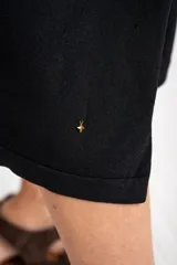 Vestido midi de punto negro con pequeño bordado de un velero en el pecho, mangas cortas y tajo lateral en el dobladillo.