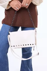 Bandolera negra de cuero sintético con solapa, decorada con tachas metálicas en la parte inferior y una cadena decorativa frontal. Incluye correa larga ajustable y extraíble.