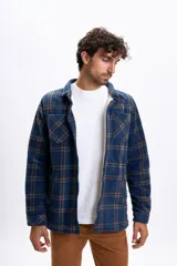 Sobrecamisa de polar a cuadros en tonos azul marino y marrón, con interior forrado en corderito, cierre frontal de botones, cuello clásico y bolsillos frontales en el pecho.