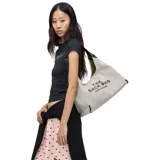 Cartera tipo hobo Marc Jacobs modelo The Belted Sack, confeccionada en lona color beige con letras negras estampadas en el frente. Presenta una forma relajada, correa de hombro ajustable y detalles en cuero negro.
