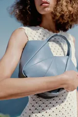 Bolso mini shopper de cuero sintético en color marrón, con diseño estructurado y costuras decorativas contrastantes. Cuenta con doble asa de mano y cierre magnético.