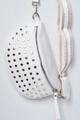 Riñonera blanca con forma de media luna, tachas plateadas y correa de tela con diseño geométrico en tonos blanco, beige y plateado.