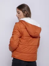 Campera puffer verde oliva de nylon con capucha forrada en corderito. Tiene cierre frontal con cremallera y botones a presión, y dos bolsillos laterales con cremallera.