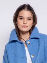 Tapado corto de paño con cuello camisero, cierre frontal de botones veteados y dos bolsillos frontales tipo parche. Presenta un diseño de corte recto y mangas largas.