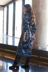 Vestido camisero largo con estampado geométrico en tonos camel y negro. Cuenta con mangas largas con puños, un bolsillo frontal amplio, botones frontales y un botón de cierre en el cuello.