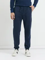 Pantalón jogging de tejido circular con cintura elástica y cordón ajustable. Presenta puños elastizados en el ruedo y bolsillos laterales.