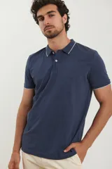 Chomba azul marino de piqué con cuello clásico y tapeta de dos botones. Detalles de ribete blanco en cuello y mangas.