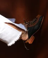 Zapato de cuero negro y marrón con cordones, detalle de textura símil cocodrilo y taco de madera.