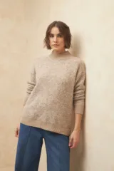 Polera beige de tejido de punto con cuello alto y mangas largas.