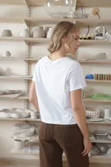 Remera negra de manga corta con escote en V, corte holgado y aberturas laterales en el dobladillo. Presenta un pequeño bordado en tono contrastante en el pecho con la inscripción "CRIADO".
