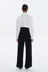 Pantalón de tiro alto, corte recto y pierna amplia, completamente cubierto de lentejuelas negras brillantes.