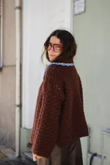 Saco tejido en crochet color marrón, con diseño de textura en relieve, manga larga y cuello grande con bordes en color celeste y crema.