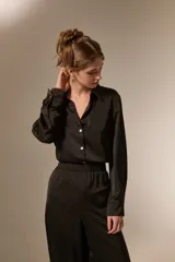 Camisa de poliéster con acabado satinado, de corte holgado, cuello camisero clásico, cierre frontal con botones y mangas largas con puños.