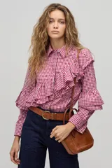 Camisa de manga larga con estampado de cuadros vichy en color rojo y blanco. Presenta cuello clásico, cierre frontal con botones de nácar y volados dobles decorativos en el frente, espalda y mangas.