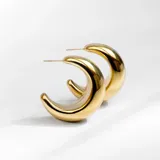 Aros tipo argolla gruesa con forma de media luna, color dorado.